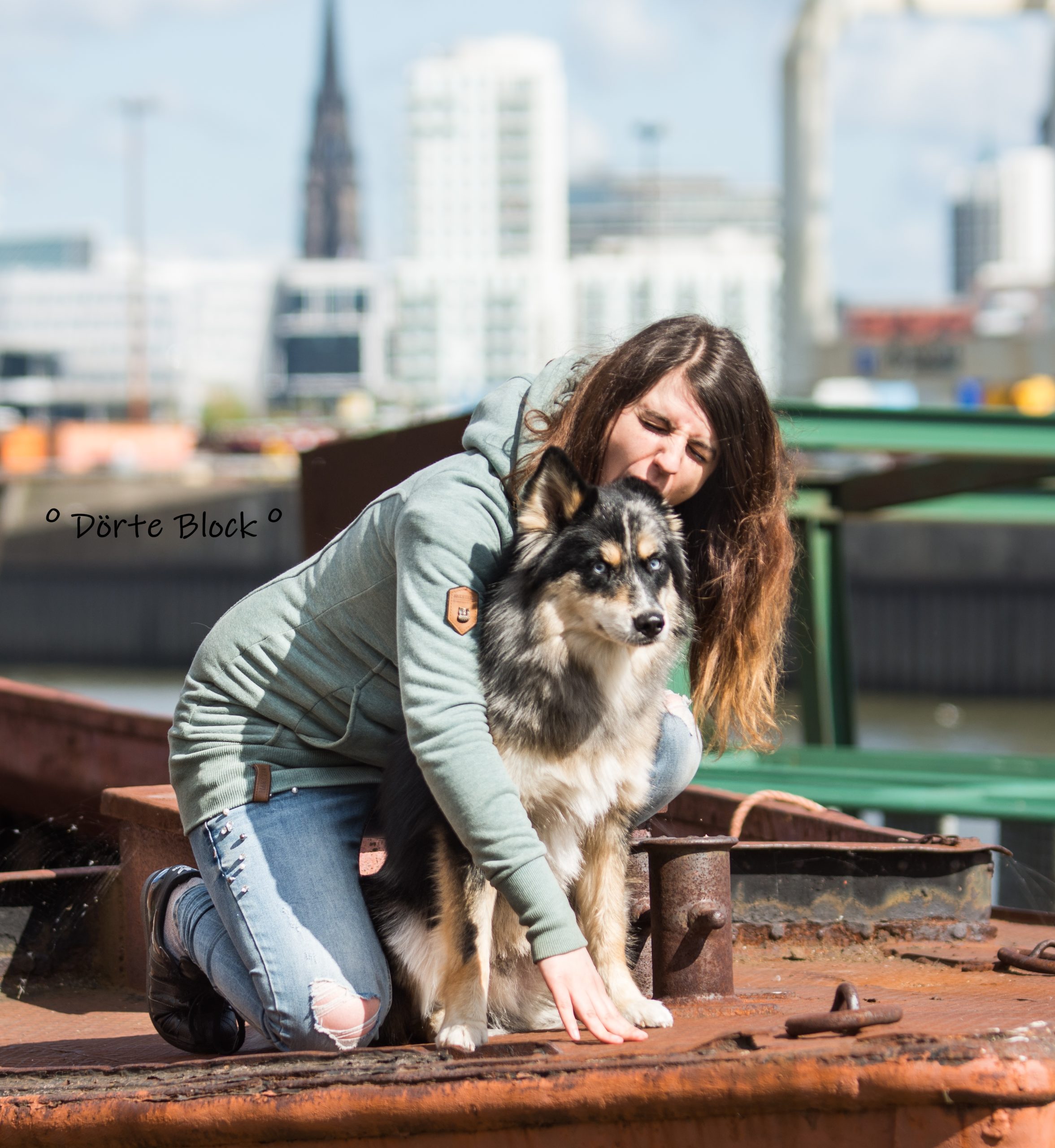 Arbiss Pomsky und Besitzerin knien auf einem alten Schiff und beißt dem Hund ins Ohr.